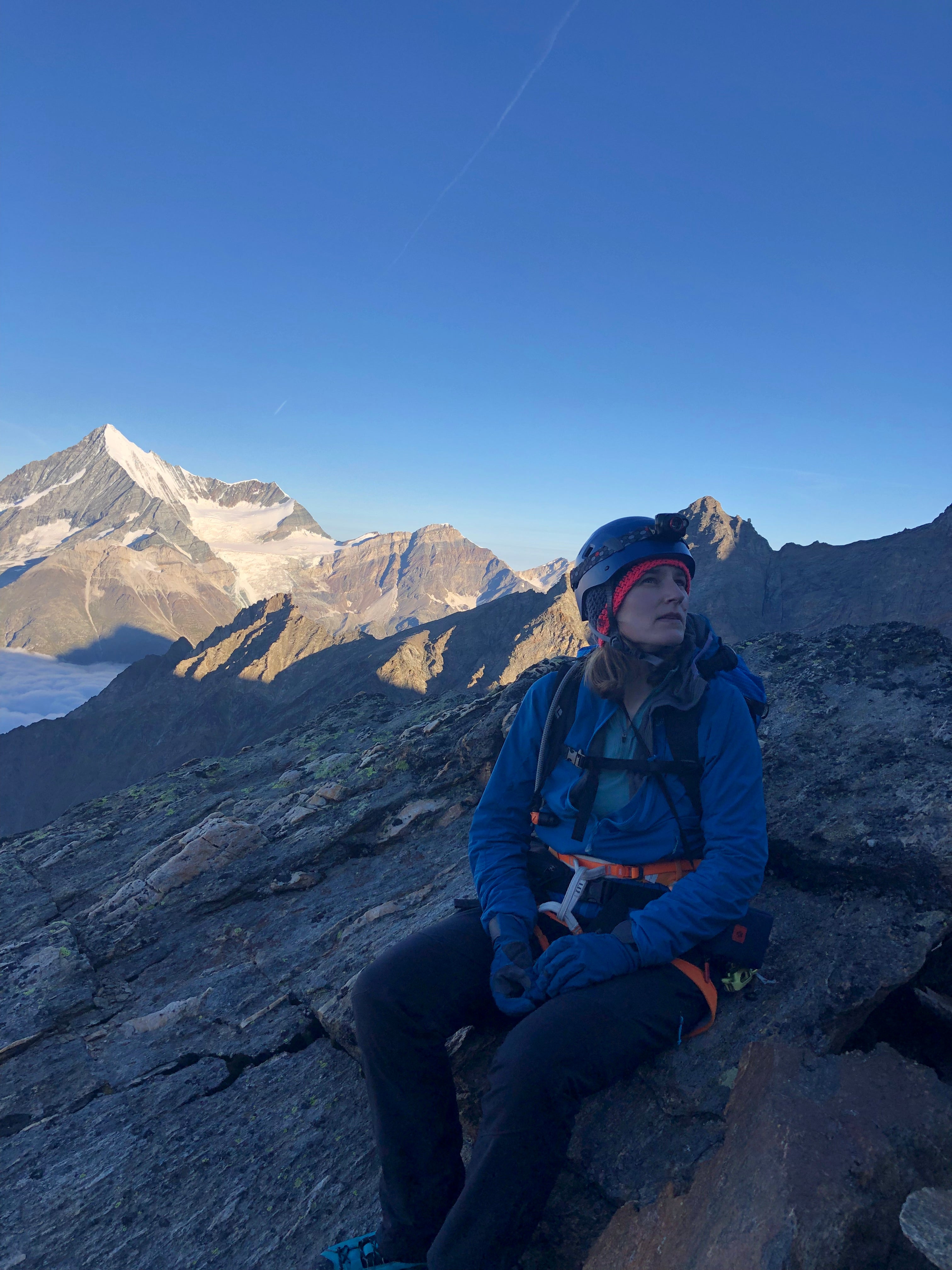 A woman climber looking at the route ahead with Alpine peaks in the background