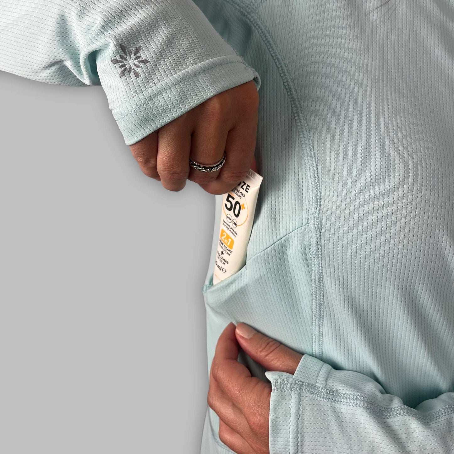 Close-up of the Soltera Hoody chest pocket holding a tube of sun cream
